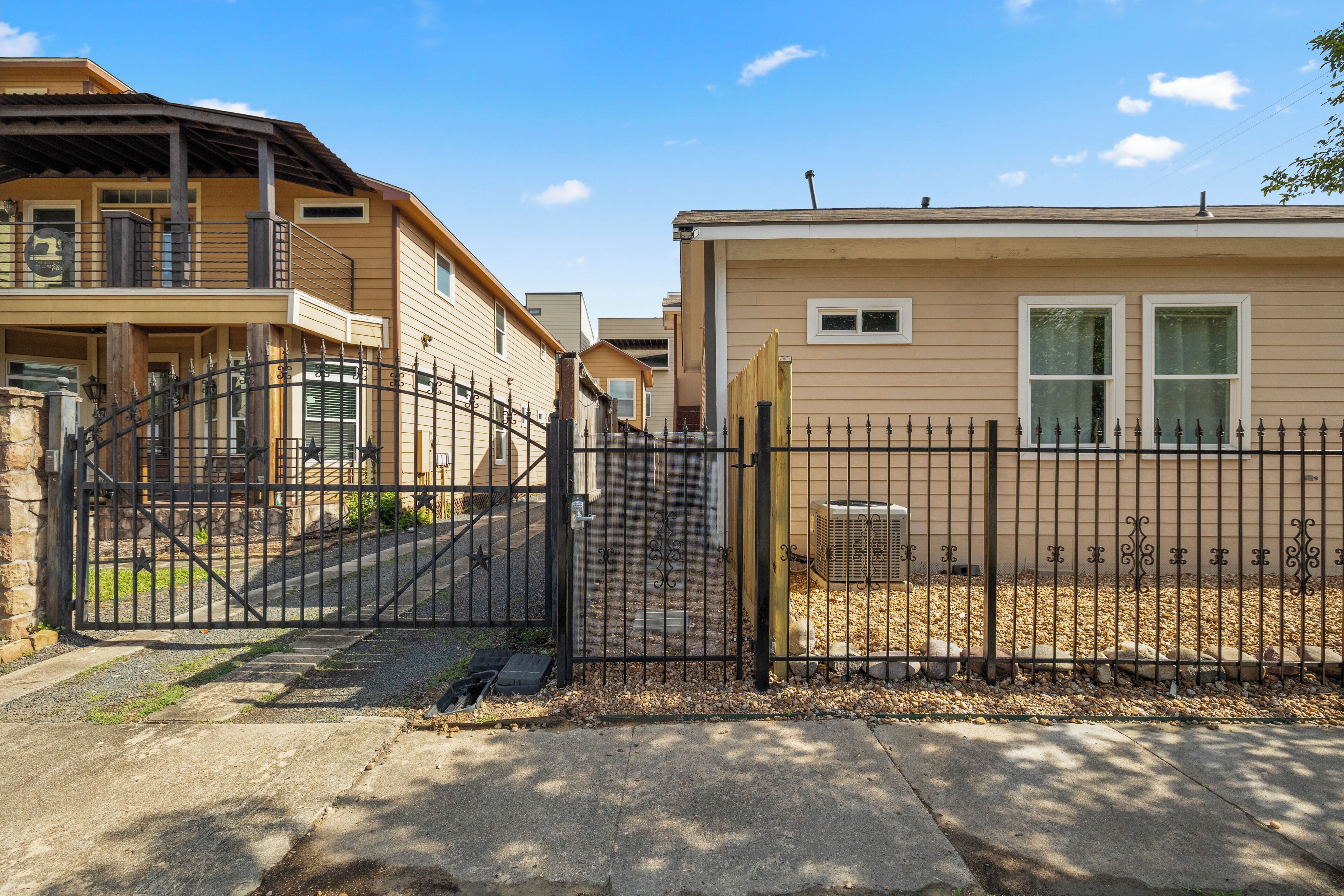A gated residential area with multiple houses, a gated entrance, and a clear sky.