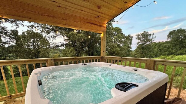 A hot tub on a wooden deck with a view of trees. - "Pike's Place" New Cabin in Daisy Ark. (Kirby)