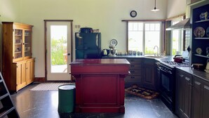 A kitchen with wooden ceiling, a central island, a refrigerator, a sink, and cabinets. - Bozeman Farmhouse Cottage (Bozeman)