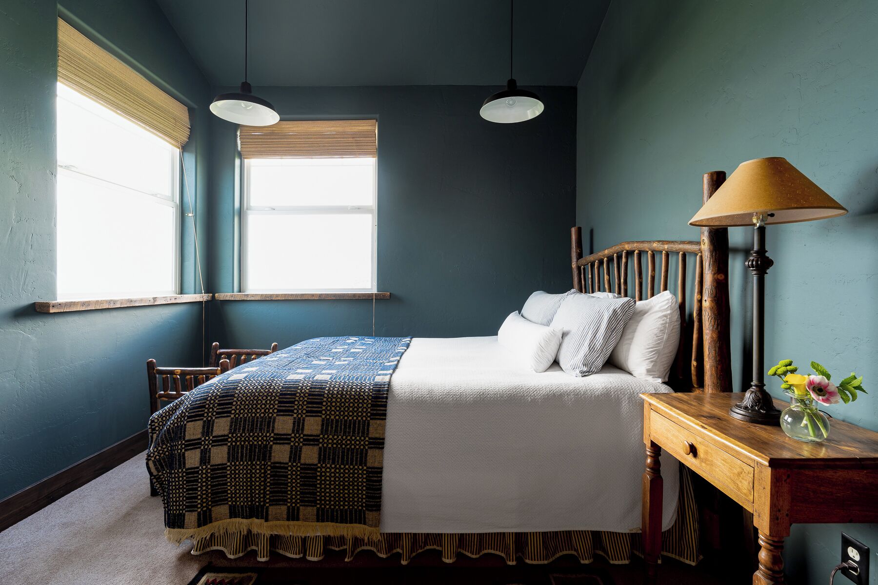 A bedroom with a bed, bedside table, lamp, and window.