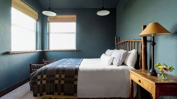 A bedroom with a bed, bedside table, lamp, and window.