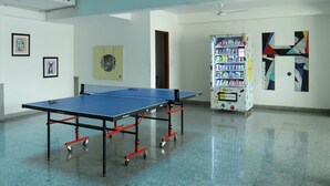 Una habitación amplia con mesa de ping pong, máquina expendedora y obras de arte en las paredes.