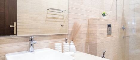A modern bathroom with a large sink, mirror, and shower.