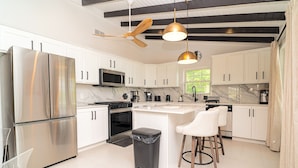 A modern kitchen with white cabinets, stainless steel appliances, a central island, and pendant lighting.
