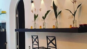 Una cocina moderna con encimera blanca, sillas negras e iluminación empotrada.