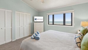 Une chambre à coucher avec un lit, un ventilateur de plafond, une fenêtre donnant sur un beau paysage et un panneau accroché au mur.