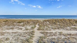 Une plage avec des dunes de sable et une vue dégagée sur l’océan.