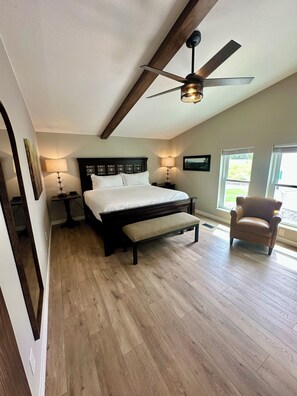 A bedroom with a bed, bench, ceiling fan, and two bedside lamps.