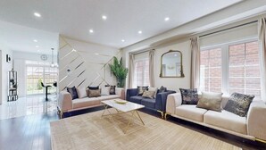 A spacious living room with a sofa set, a coffee table, and a large window with curtains.