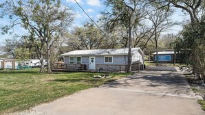 A single-story mobile home with a front porch, a small attached garage, and a paved driveway leading to the entrance.