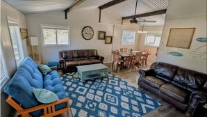A spacious living room with a blue sofa, a brown leather couch, and a dining area with a table and chairs.