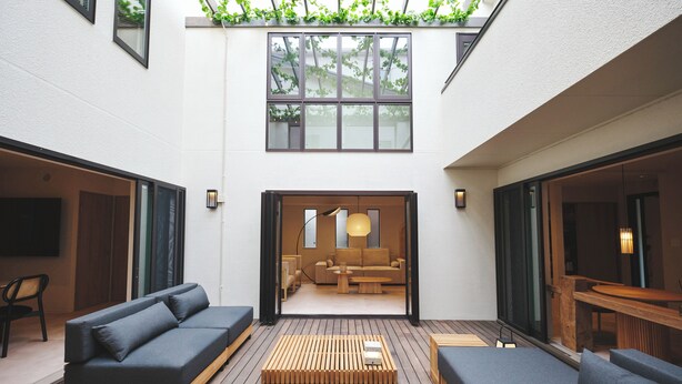 Ein moderner Außenbereich mit Holzboden, Sofas und Blick in einen gemütlichen Innenraum.