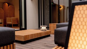 Ein modernes Interieur mit einem Holztisch, zwei grauen Sofas und einer kleinen beleuchteten Tischlampe.