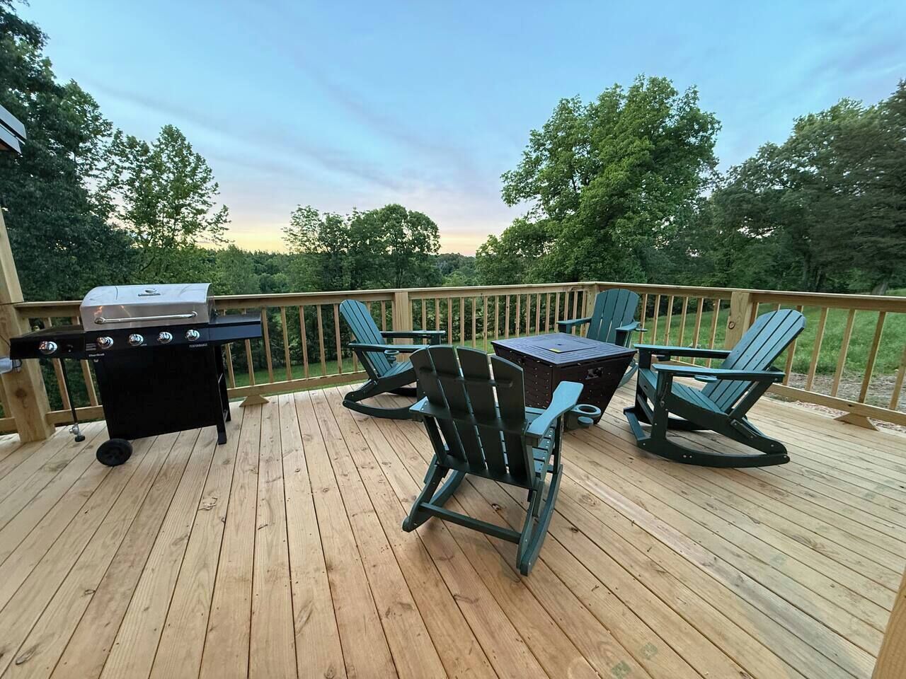 A wooden deck with a grill, chairs, and a table.