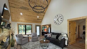 Un salon spacieux avec un haut plafond, une grande horloge et une cheminée accueillante.