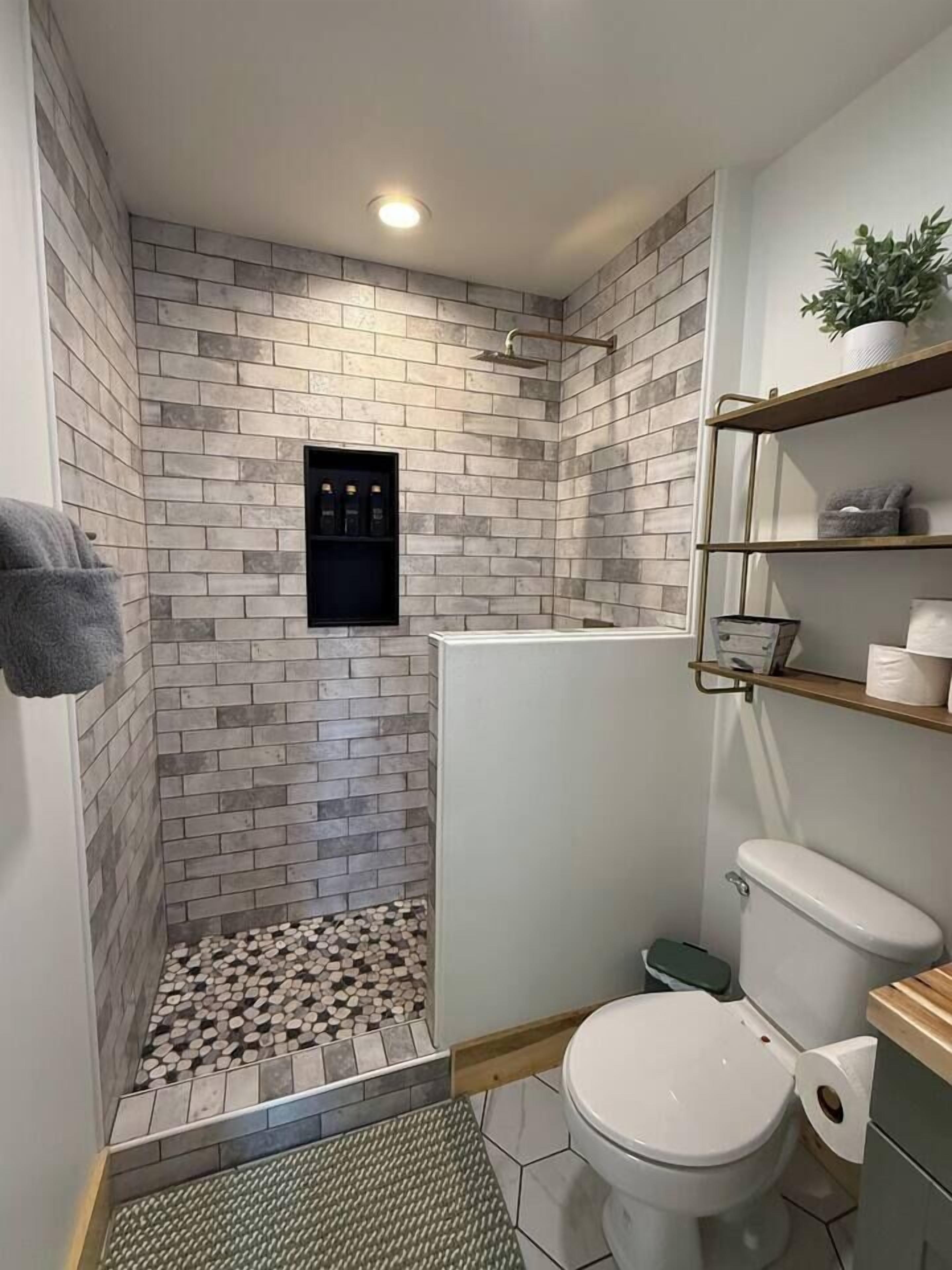 Ein Badezimmer mit Dusche, Toilette und Ablagen für Toilettenartikel.