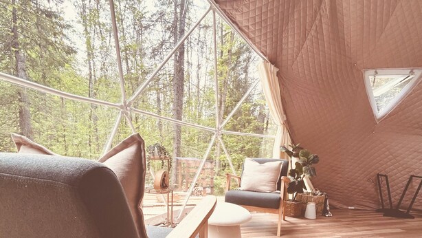 A tent with a wooden floor and furniture including a sofa and a chair. - • TRANQUILITY DOME• OFFGRID GLAMPING RETREAT IN PRIVATE FOREST! (Killaloe)