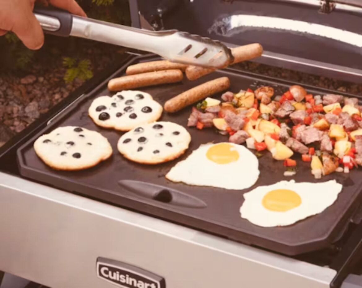 A Cuisinart grill with cookies, eggs, sausages, and a vegetable mix being cooked.