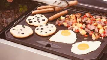 A Cuisinart grill with cookies, eggs, sausages, and a vegetable mix being cooked.