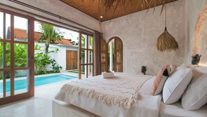 A bedroom with a large bed, a view of a swimming pool, and a rustic ceiling. - Nick Villas by Villa Finder (Ubud)