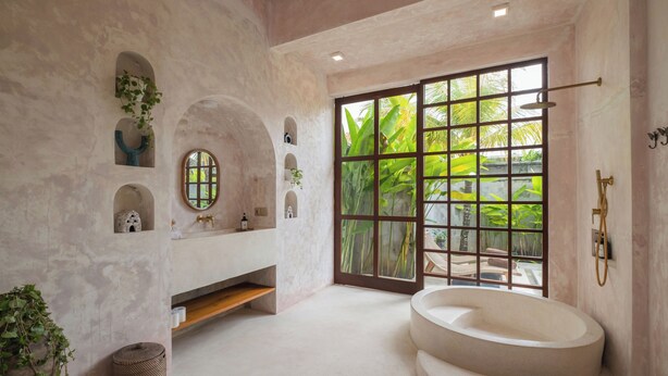 A bathroom with a freestanding bathtub, a large window with a view of greenery, and a vanity with a mirror and sink. - Nick Villas by Villa Finder (Ubud)