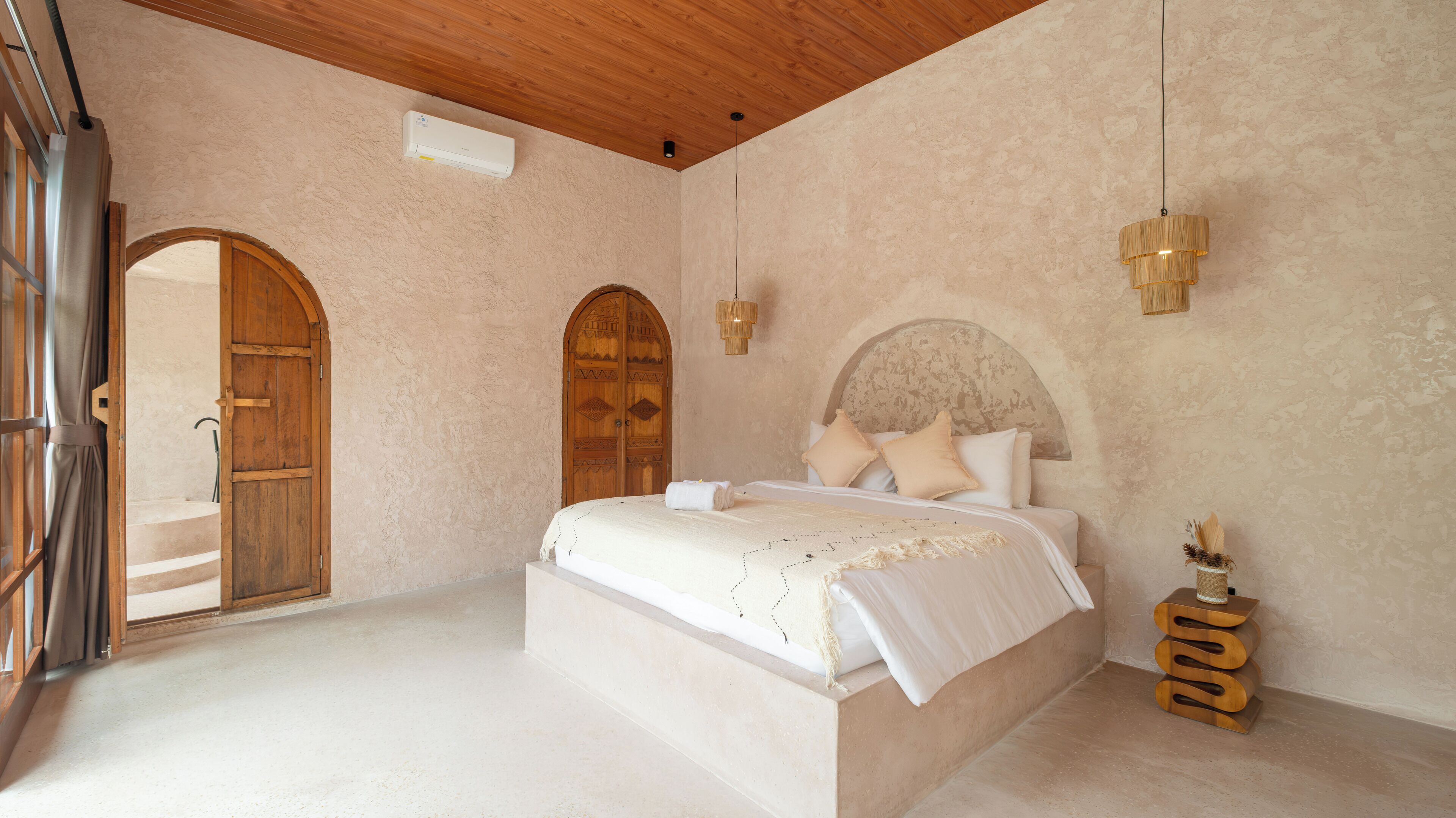 A spacious bedroom with a large bed, wooden doors, and a ceiling fan.
