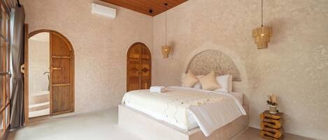 A spacious bedroom with a large bed, wooden doors, and a ceiling fan.