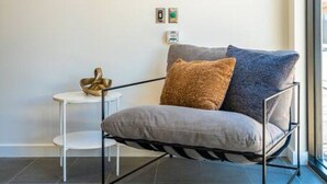 Ein modernes Zimmer mit einem stahlummantelten Stuhl, einem kleinen weißen Beistelltisch und einem an der Wand befestigten Schild mit der Aufschrift 'SYLO'.