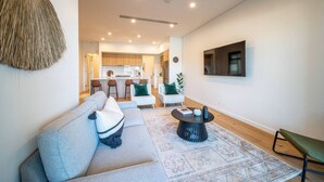 Ein modernes Wohnzimmer mit einer Couch, einem Couchtisch und einem an der Wand montierten Fernseher.