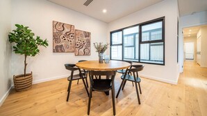 A modern dining area with a round wooden table, black chairs, and a potted plant.