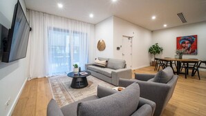 Una sala de estar moderna con un sofá gris, una mesa de centro y un comedor con mesa y sillas.