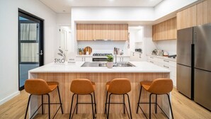 Una cocina moderna con una isla central, armarios de madera y un refrigerador de acero inoxidable.