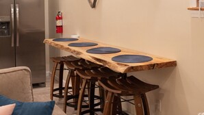 A kitchen with a wooden bar table, stools, a refrigerator, and a fire extinguisher. - The Nautilus at JS Hubbs Guest House (Hammondsport)