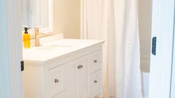 Une salle de bain avec un meuble-lavabo blanc, un miroir et un rideau de douche.