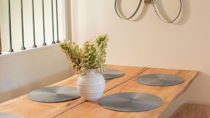 Una mesa de comedor con un florero y manteles individuales grises.