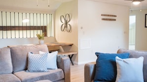 Una sala de estar moderna con un sofá, una mesa de centro de madera y decoración en la pared.