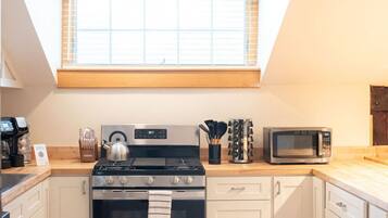 Una cocina moderna con estufa a gas, horno, microondas y encimera de madera.