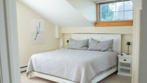 Un dormitorio con cama, mesitas de noche y ventana.
