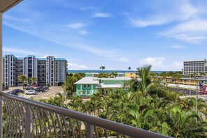 A coastal residential area with multi-story buildings, a parking lot, and a view of the ocean.