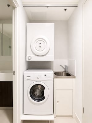 A compact laundry room with a washing machine, a dryer, and a sink.