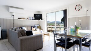 A modern living room with a sofa, TV, and dining area with chairs and a table.