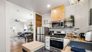 A modern kitchen with a central island, stainless steel appliances, and a herringbone wood backsplash. - Historic 2BR Prescott Home | Walk Downtown (Prescott)