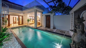 A modern house with a swimming pool, a covered patio, and a statue.