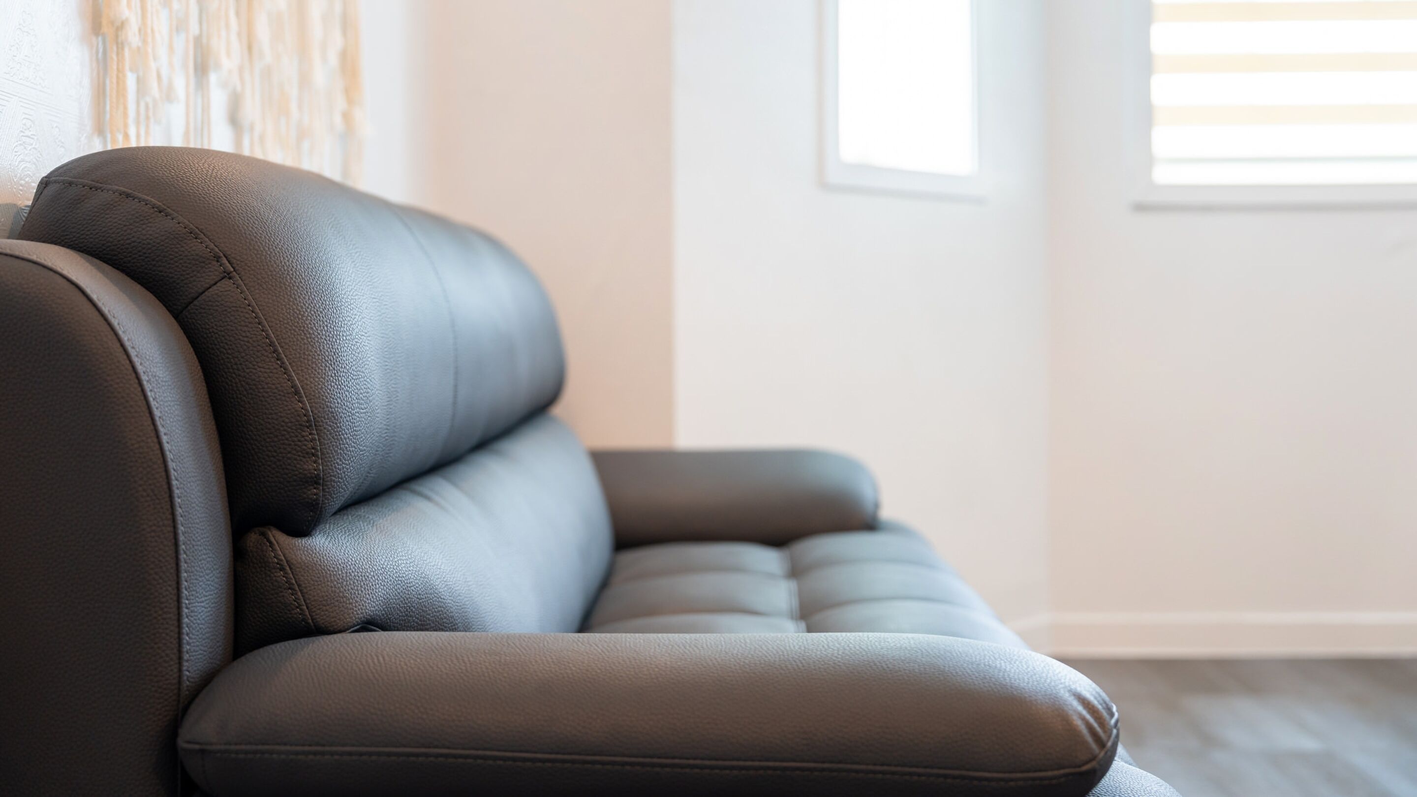 Parte de un sofá moderno de color oscuro en una habitación con decoración minimalista.