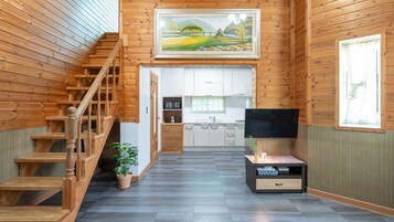 Un interior de madera con una escalera, una cocina y un televisor.