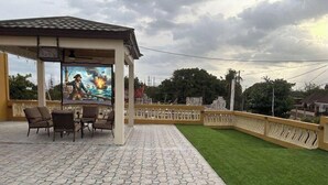 An outdoor patio with a gazebo, a mural, and a well-maintained lawn.