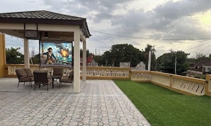 An outdoor patio with a gazebo, a mural, and a well-maintained lawn.