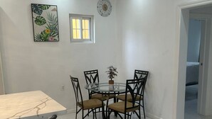 A dining area with a round glass table, black chairs, and a marble-top table.