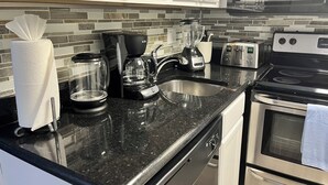 Eine Küche mit Granit Arbeitsplatte, einer Kaffeemaschine, einem Toaster und einem Geschirrspüler.