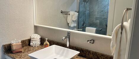 A bathroom with a white sink, granite countertop, and a large mirror above the sink.